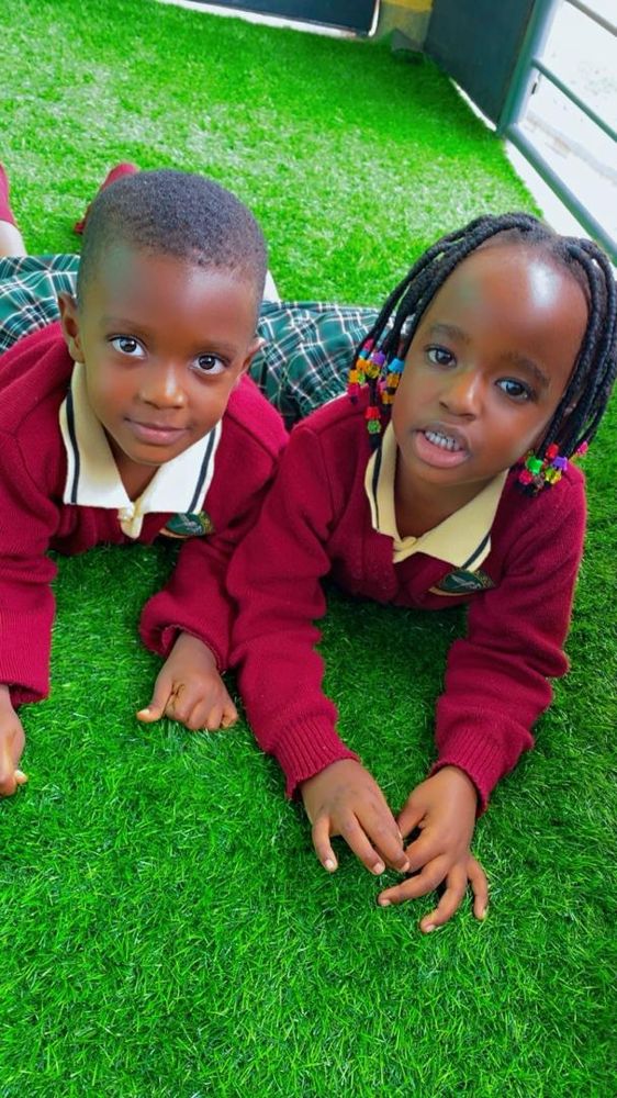 Two Grivillea pupils in maroon uniform smiling on the grass
